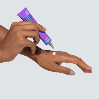 Pessoa aplicando o Sérum Antissinais da Sallve na mão. A imagem mostra a textura cremosa e amarelada do produto, com bisnaga roxa e aplicador de precisão.