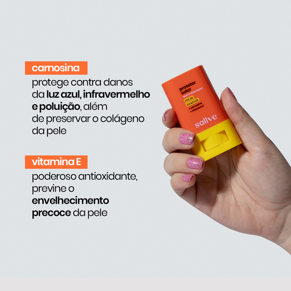 Mão segurando o Protetor Solar Bastão FPS 60 Muito Resistente da Sallve com destaque para os ativos carnosina e vitamina E, que protegem contra luz azul e envelhecimento precoce.