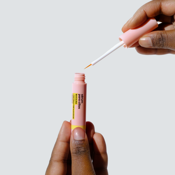 Pessoa segurando o sérum para cílios Sallve e mostrando o aplicador com ponta fina.