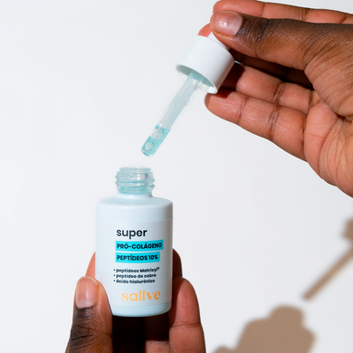 Mão segurando o Super Pró-Colágeno 10% da Sallve com o conta-gotas mostrando a textura fluida azulada do produto.